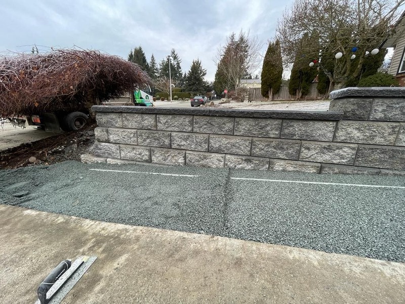 the north side allan block wall complete with crusher fines installed for the drive way extension. a screed poleis in the crusher fines 
