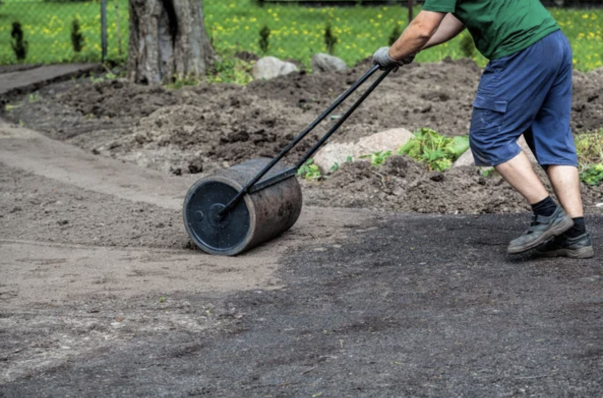 a man using a lawn roller to roll fresh soil